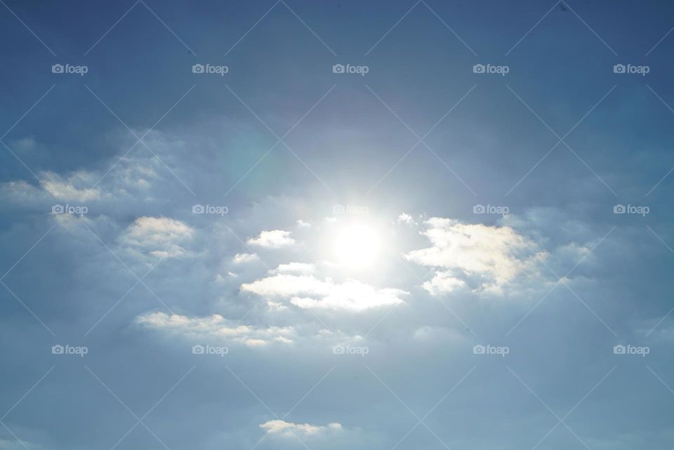 Sun in the sky with clouds over a lake in Michigan