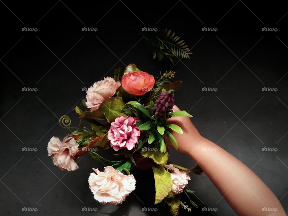 hand on artificial flower arrangement.