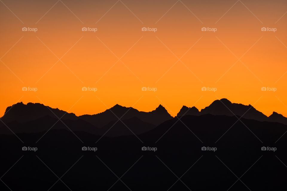 Bright orange sky over a silhouette mountain background, just before sunrise