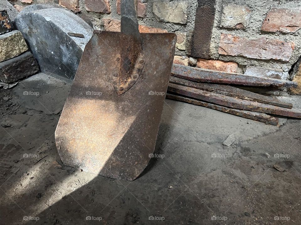 Rustic old spade standing against brick wall 