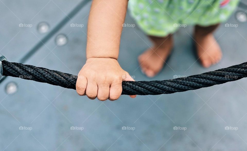 Child hanging onto merry go round, toddler riding on carousel, toddler hand gripping rope, hand holding on to ride 