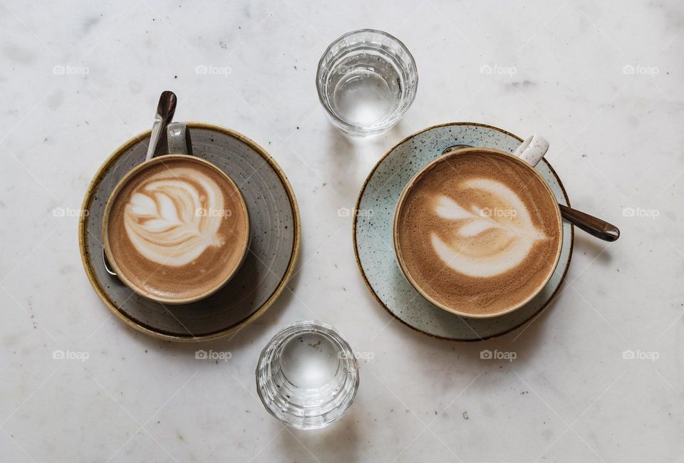 Top view of two cups of coffee with latte art on table in cafe