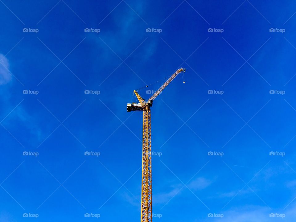 Yellow tower crane in front of blue sky 
