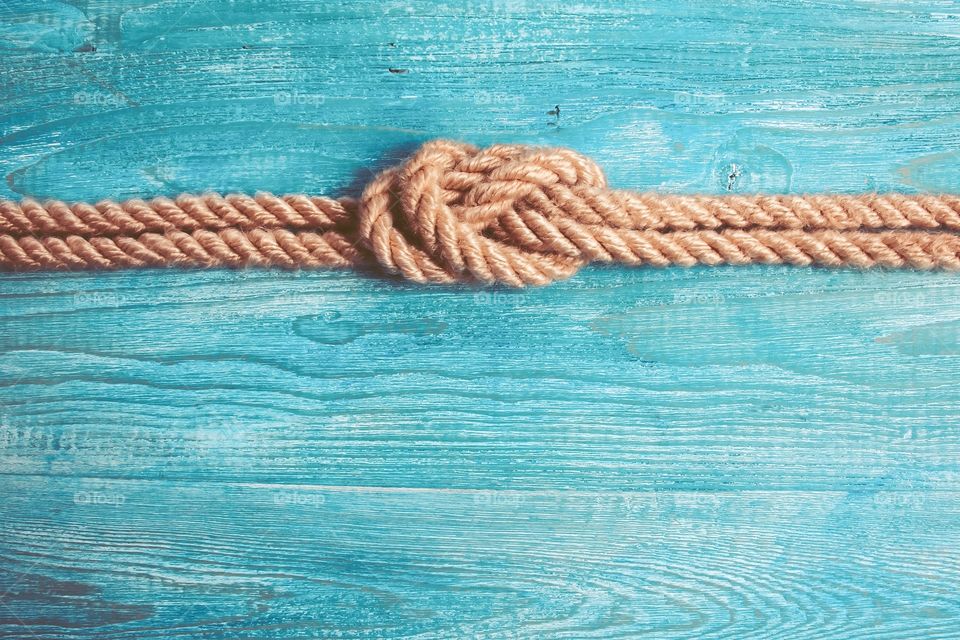 Sea knot on a rope on a blue wooden background.