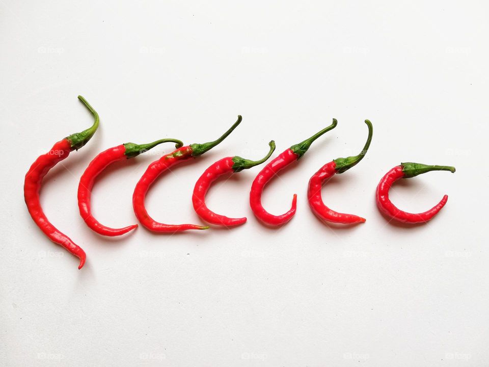 red chillies in a row on white background