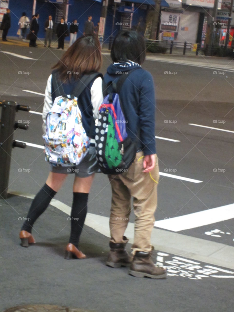 Young Japanese Couple Holding Hands in Tokyo, While Businessmen Talk in the Street.  Modern vs Traditional