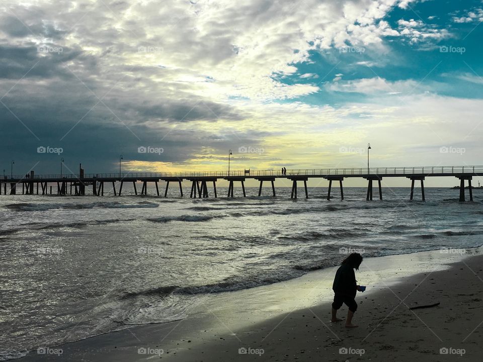 Jetty pier dock at sunset girl child playing foreground silhouetted