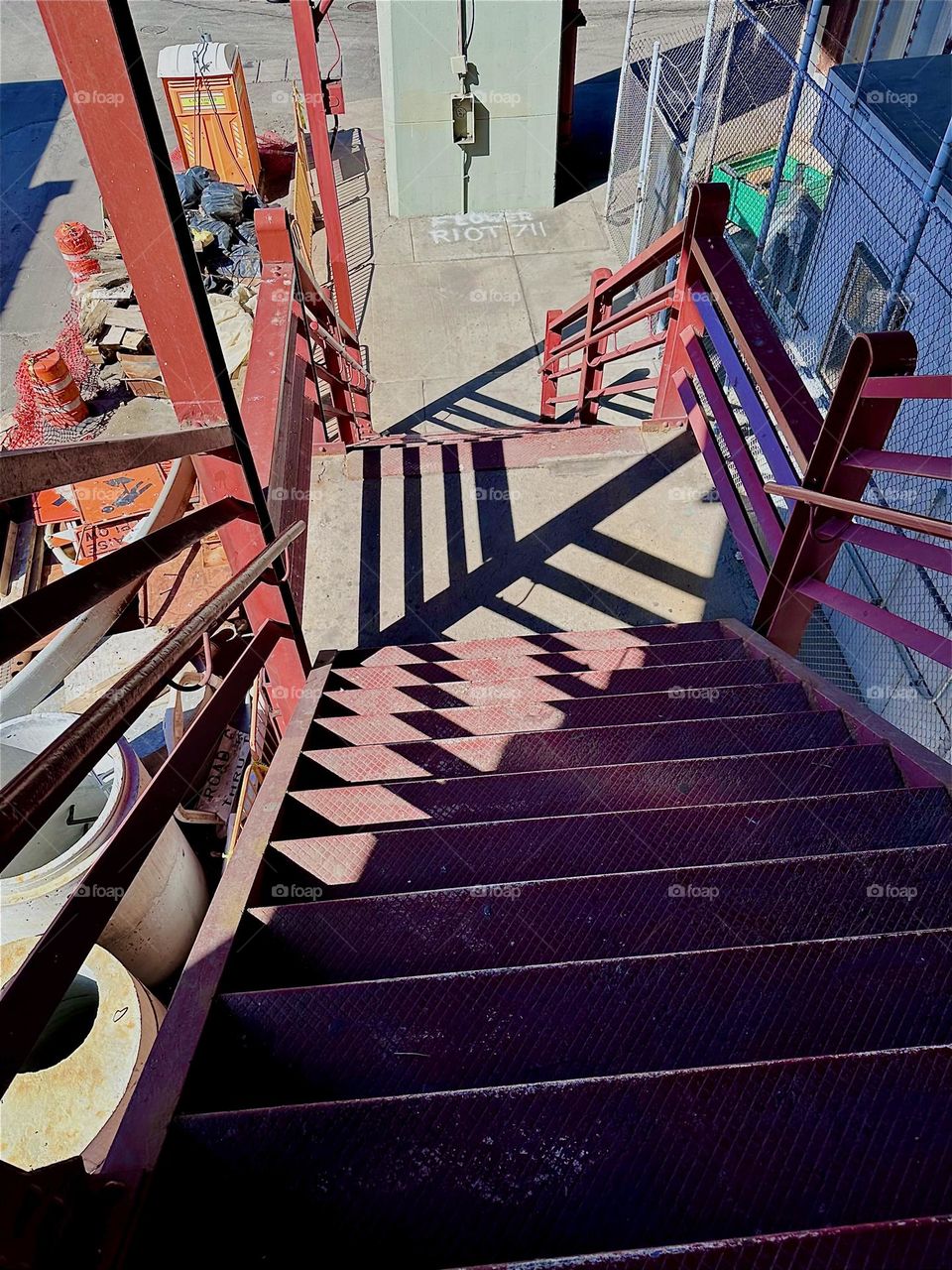 This is the descending red metal staircase of the “Pulaski Bridge” at “Newtown Creek” in LIC, Queens. The afternoon sun casts deep shadows that are displaced by the shape of the steps thus creating multifaceted patterns. 2024. Hypnotic Productions