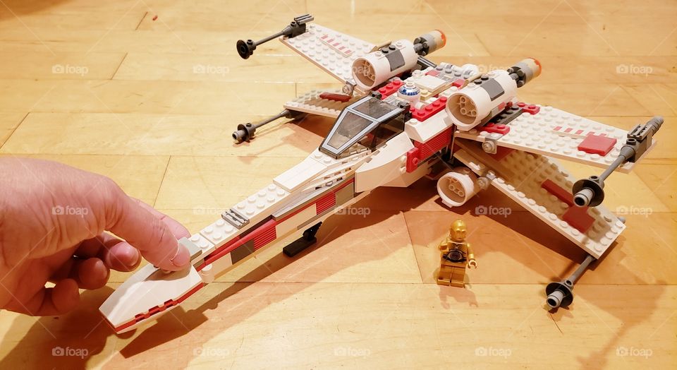 Putting on the final Lego tile to create the Star Wars  X-Wing.