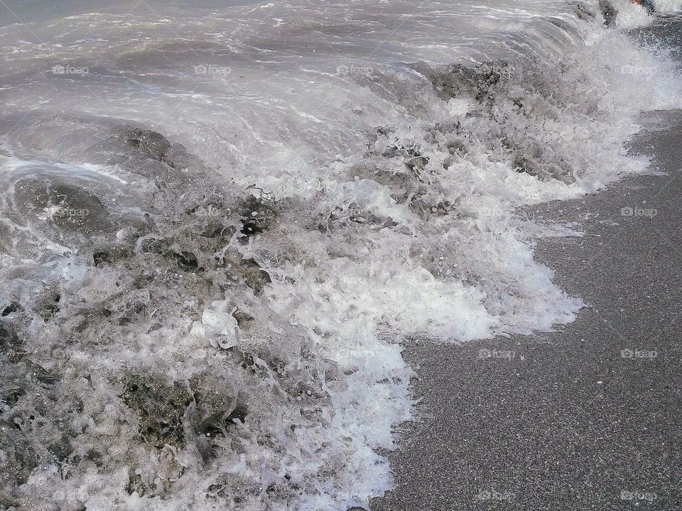 Waves rolling in the sand on a grey stormy summer day at the beach off the Gulf Coast of Florida.
