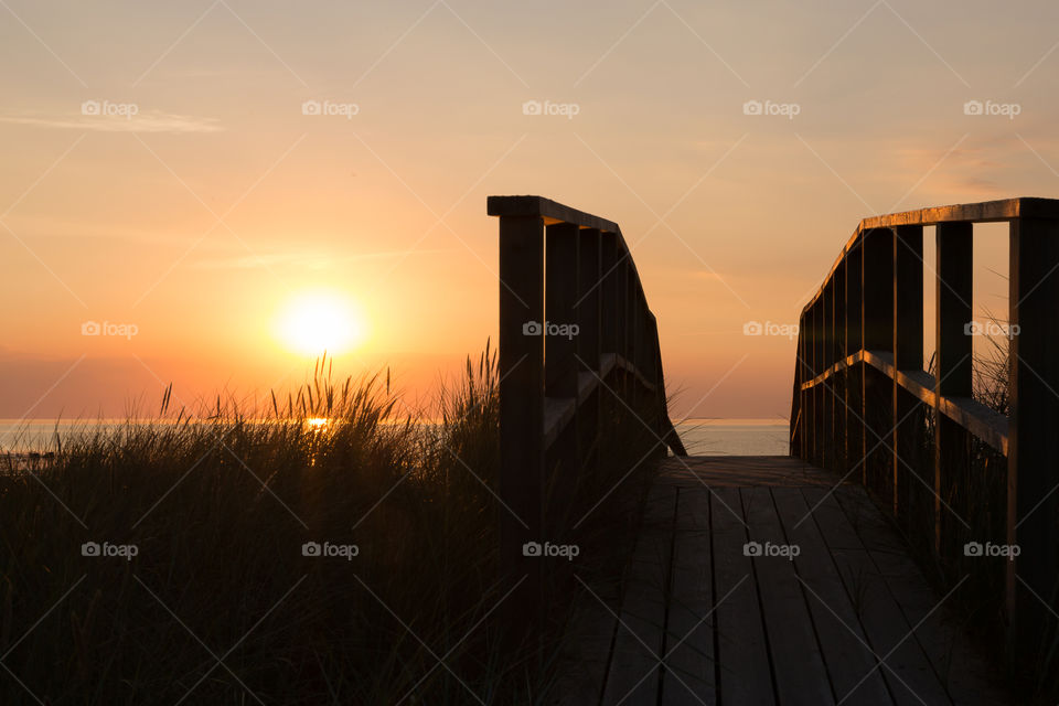 Wooden boardwalk leading to the ocean, beautiful warm colors at sunset in golden hour 