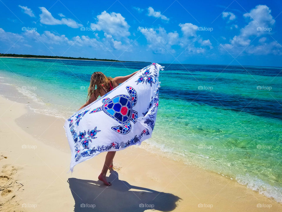 A girl dancing around the beach with her turtle cover up