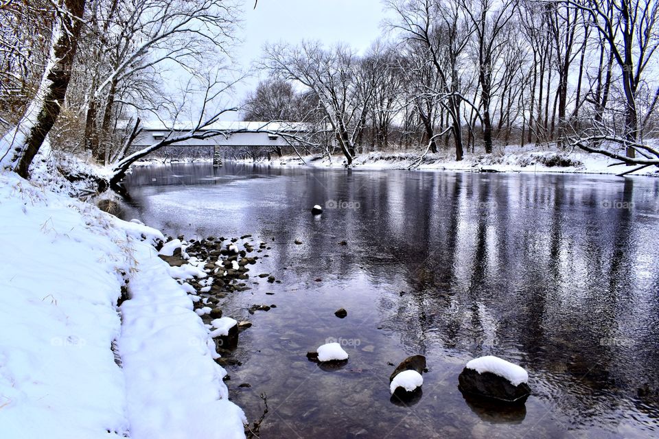 A winter day on the white rover in Indiana with the old covered bridge and a reflection on the water 