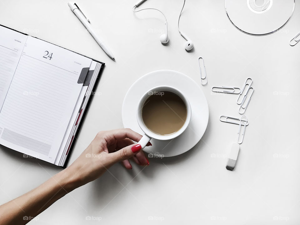 Female hand holding a coffee cup on the white desk