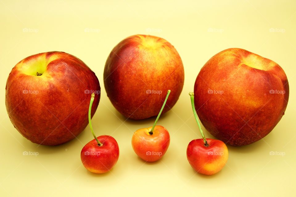 Fruits! - Nectarines And Rainer cherries against a yellow background 