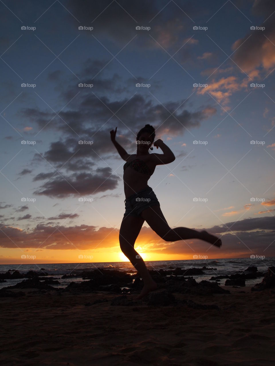 Silhouette of girl jumping on the beach at sunset.  