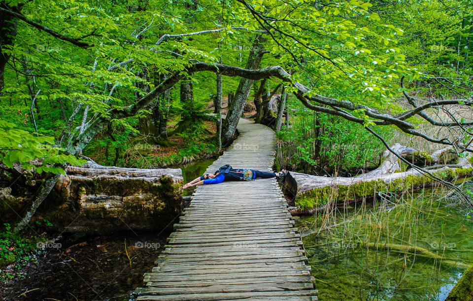 Woman lying on boardwalk in the forest