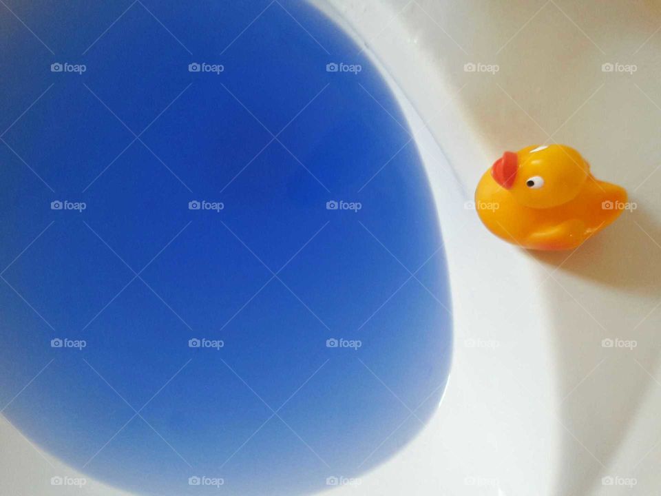 Rubber duck beside sink with blue water