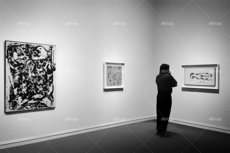 A woman looking at Jackson Pollock art work at a DallasTexas museum in black and white