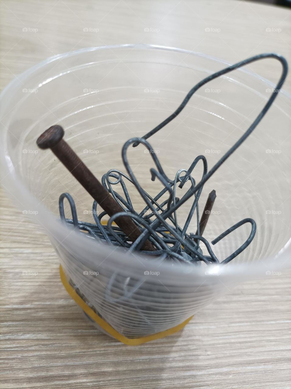 copo cheio de pregos em cima da mesa
