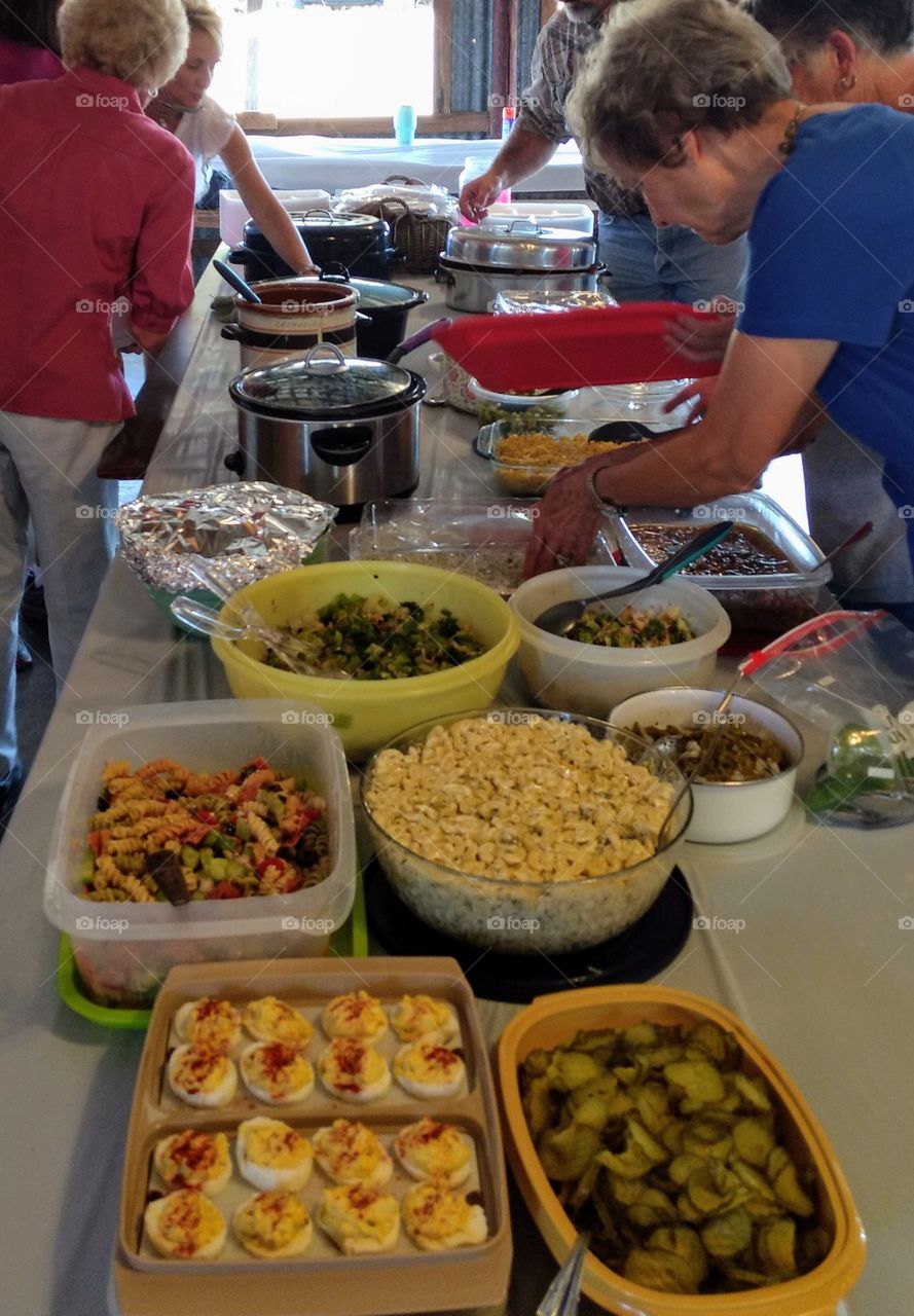 Potluck lunch dinner, family reunion, salads, foods, picnic BBQ table with food, rural casual meal, colorful, sharing