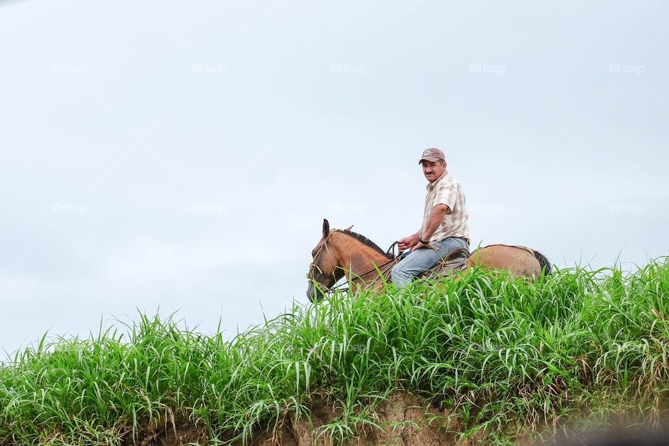 A man on a horse. A Costa Rican man riding a horse in the fields