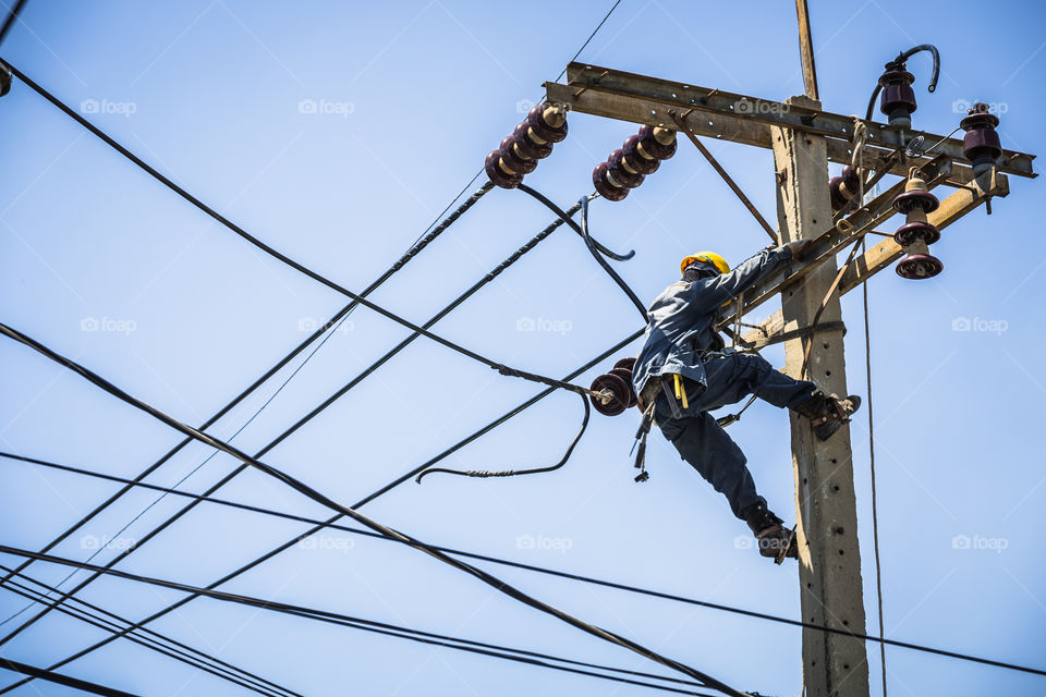 Electrician working on the electricity pole to replace the electrical insulator