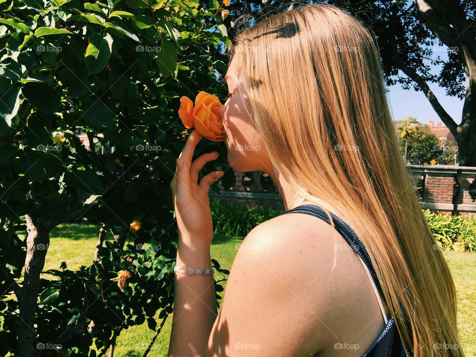 girl smelling orange rose