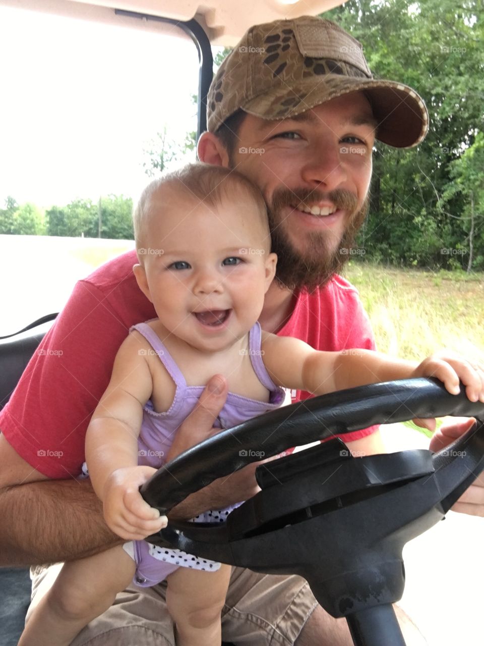 Cute baby with father holding steering wheel