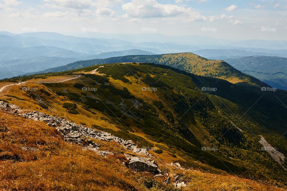 Mountain landscape. Scenic view of mountain peaks, slopes, hills and valleys covered with grass and trees. Panoramic view. Natural scenery. Beautiful background