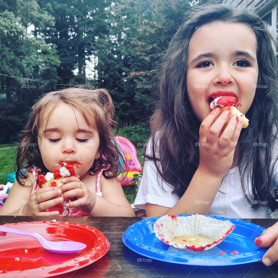 Portrait of two girls eating cake