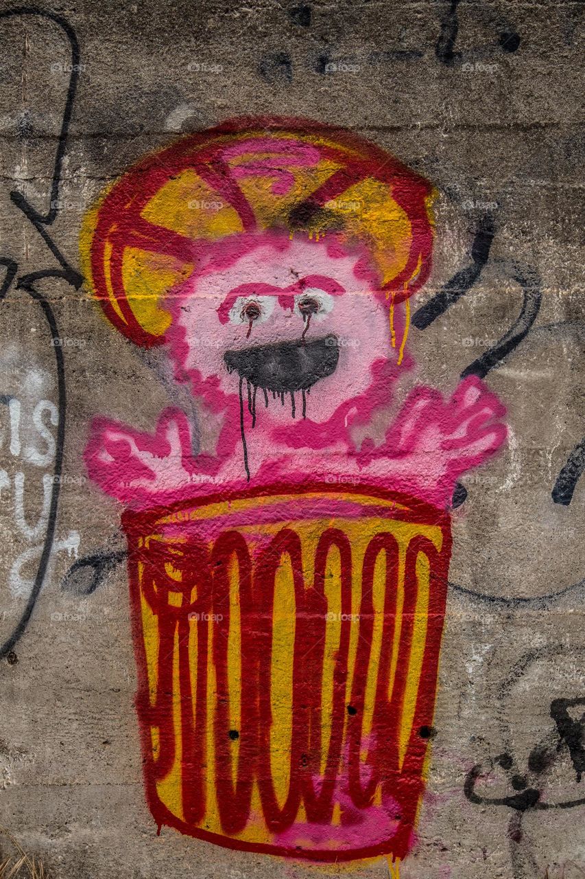 Oscar the grouch graffiti in pink like Barbie on a cement wall 