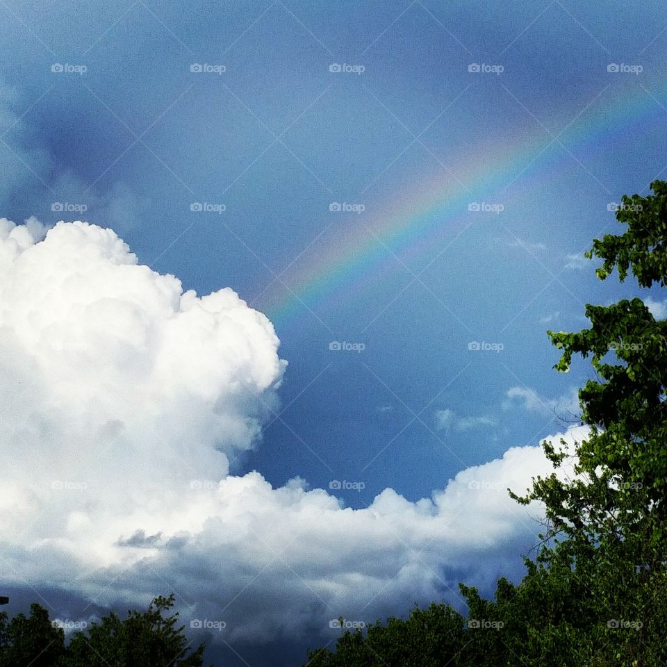 Rainbow coming up from cloud after a storm