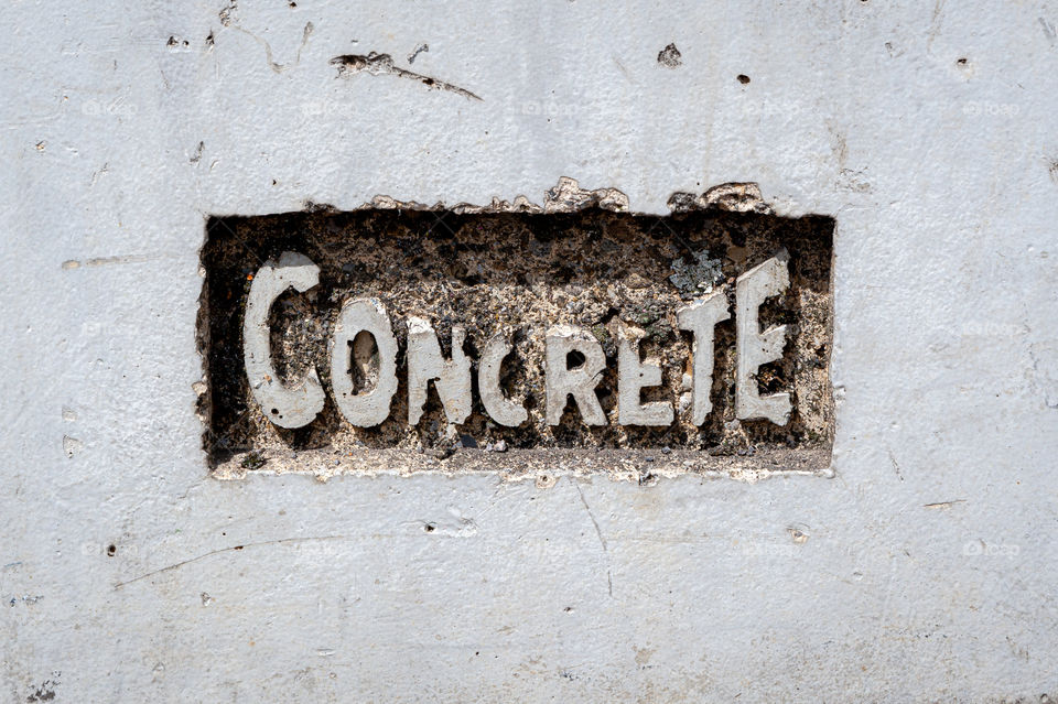 A word concrete carved into a grey concrete wall.