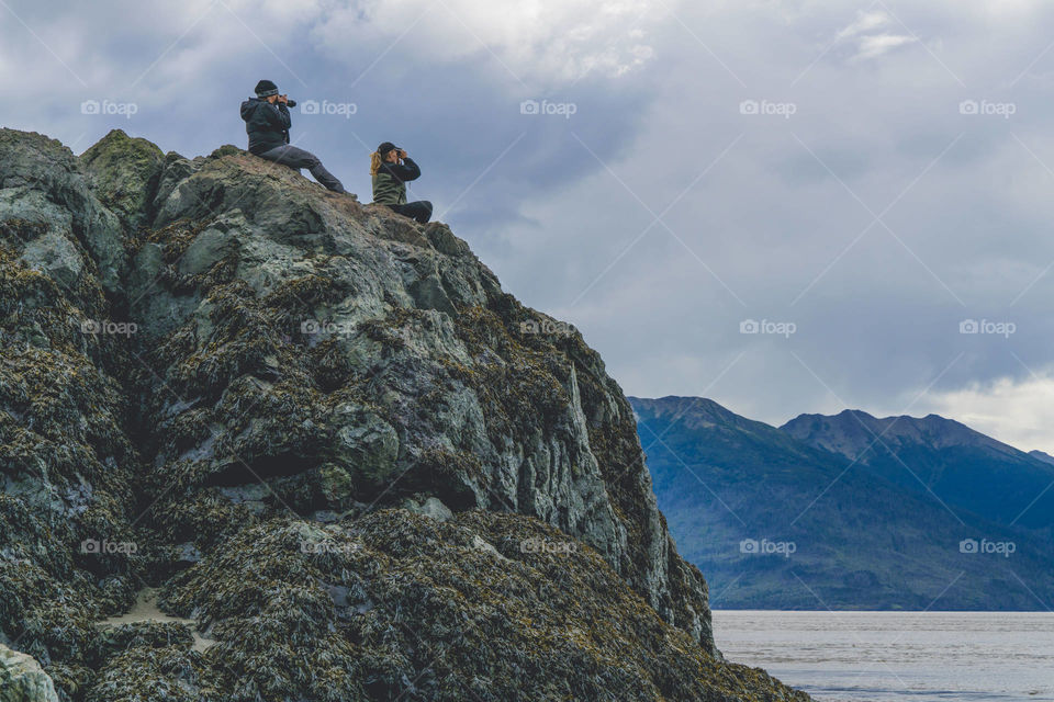 Spectators view nature from a large rock. 