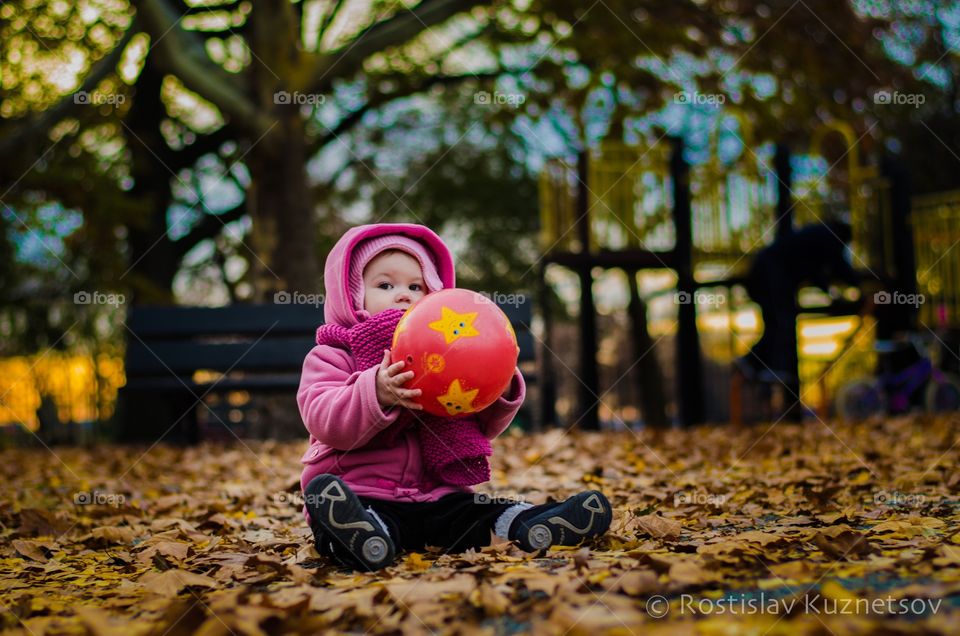 Little girl sitting in park with ball