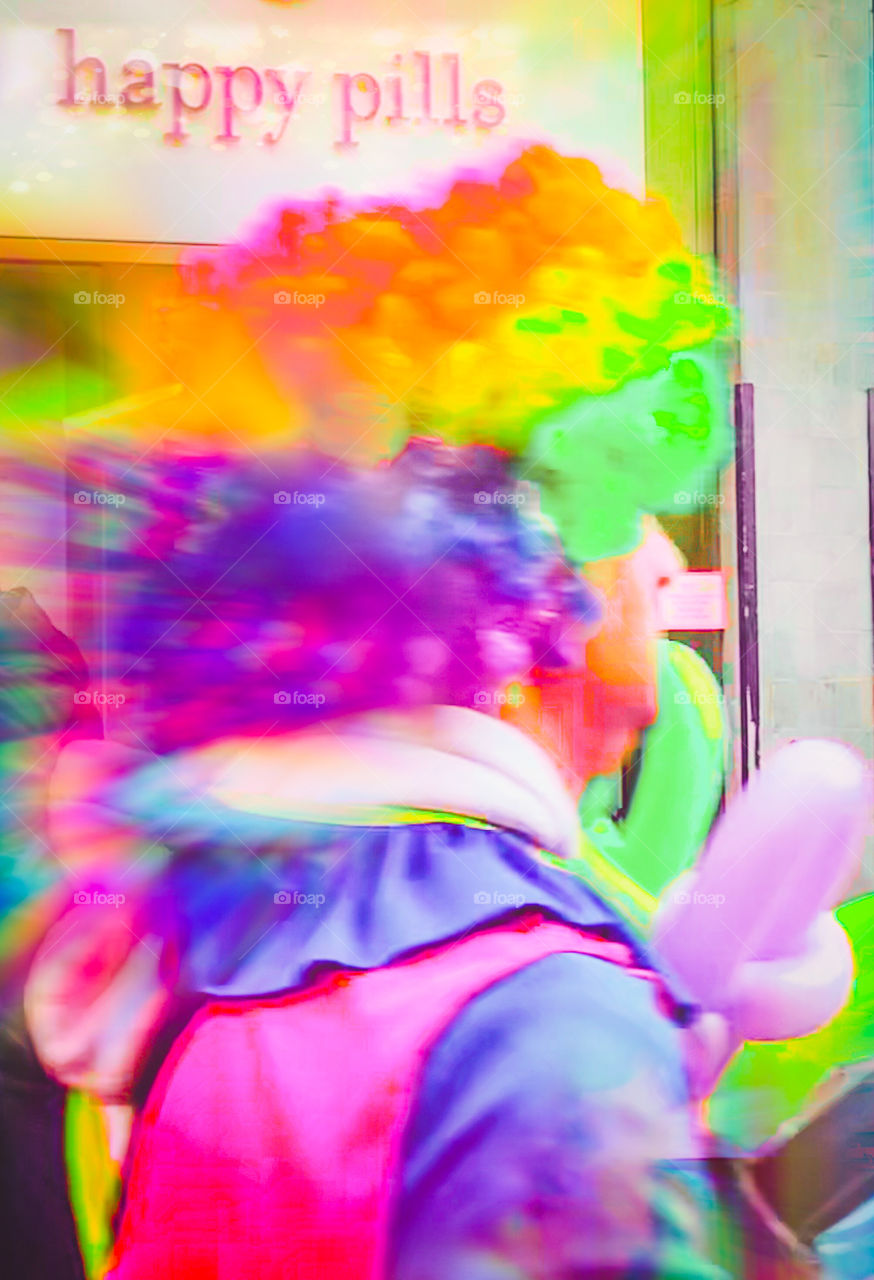 A brightly coloured clown, briskly past a sign reading Happy Pills. The image is heavily saturated.