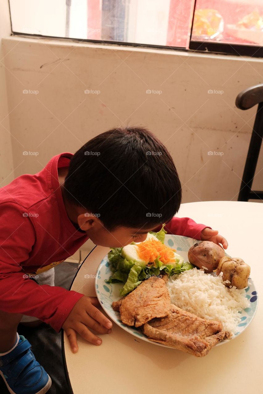 Child eats a plate of fried fish