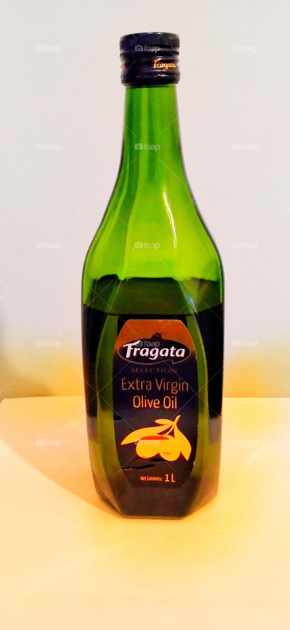 A bottle of olive.green colour of a bottle and with a white background.