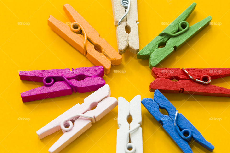 colorful wood decorative clothespins on a yellow background , close up. Magic of colors in daily routine concept