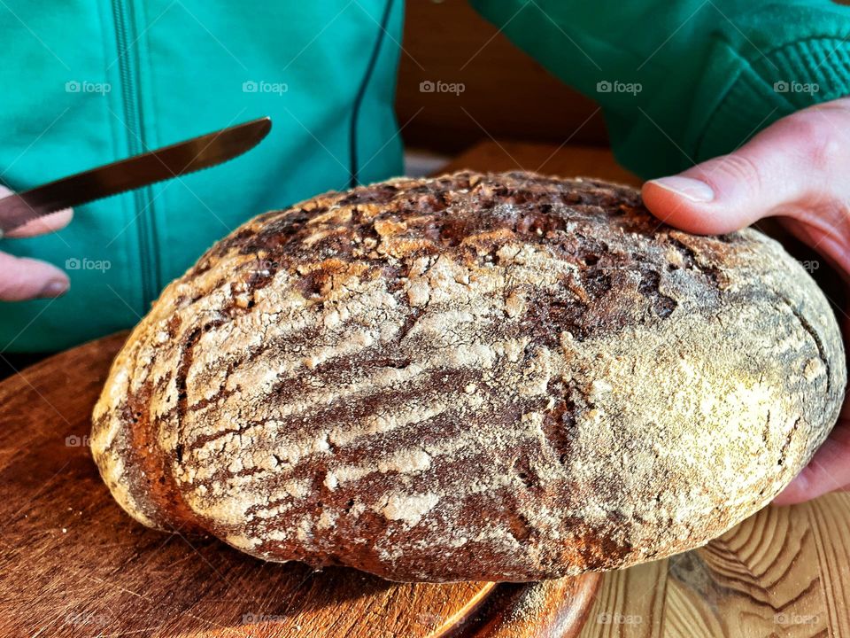 Close up of fresh dark bread being sliced