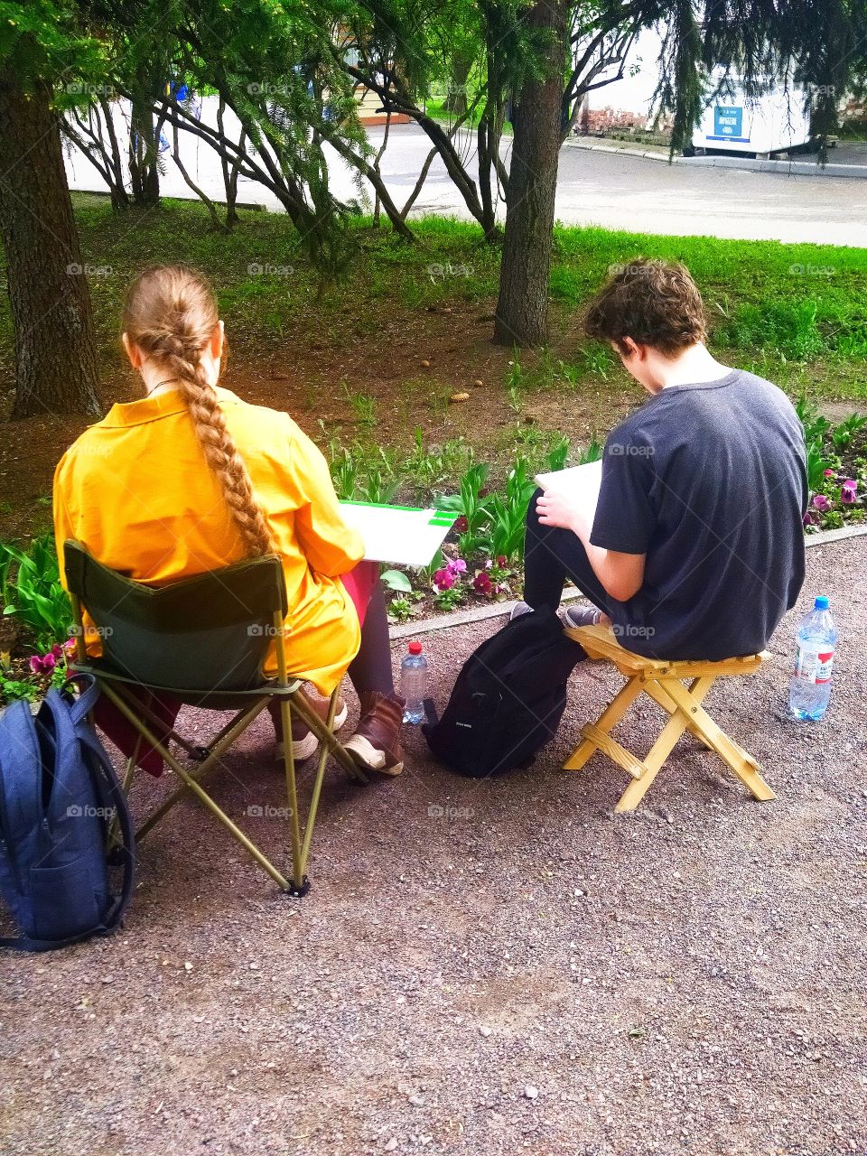 Summer.  Girl and boy sit on folding chairs and draw