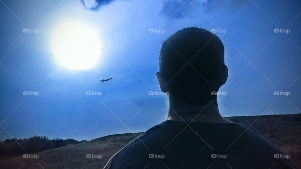 Man looking at commercial airliner at sun down