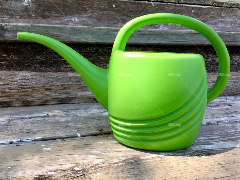 Green Color Story - plastic watering can on wooden steps in sunlight 