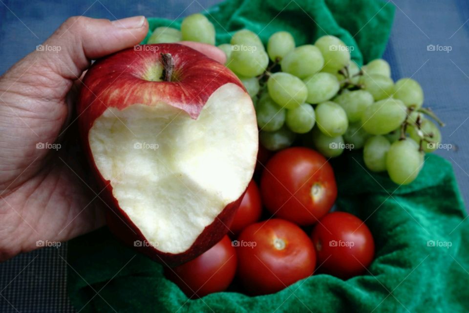 Hand of person holding bitten apple