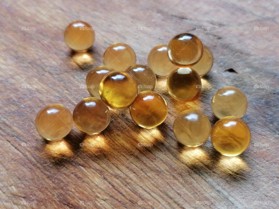 a few fish oil pills. small translucent balls on a wooden