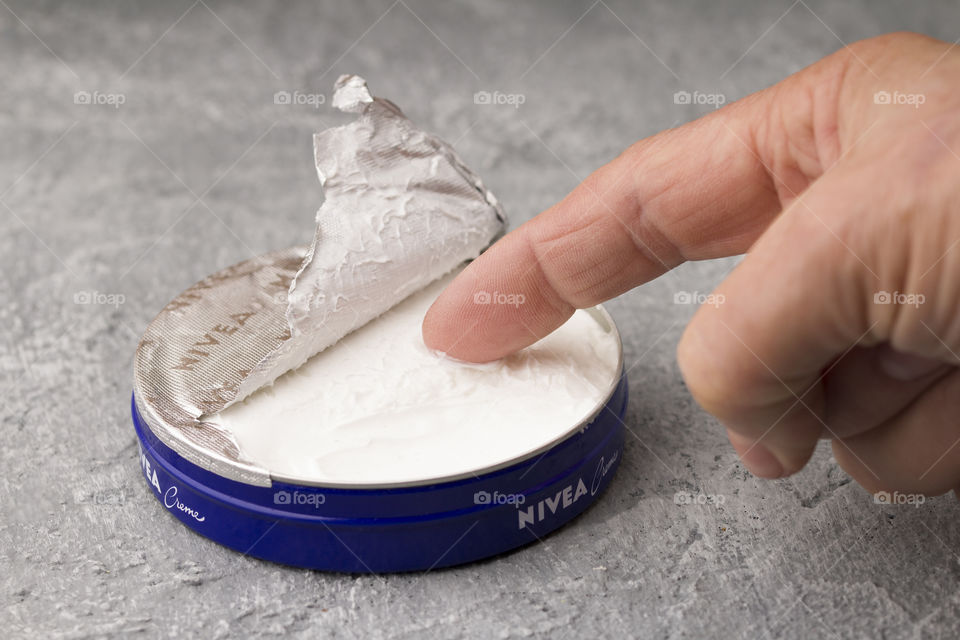 close up of Nivea creme and finger. body care concept,  daily routine