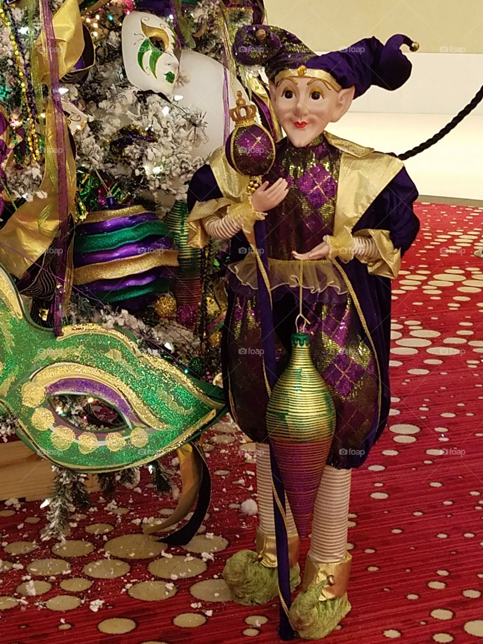 Purple, Mardi Gras Jester dressed in purple surrounded by purple Mardi Gras ornaments and mask
