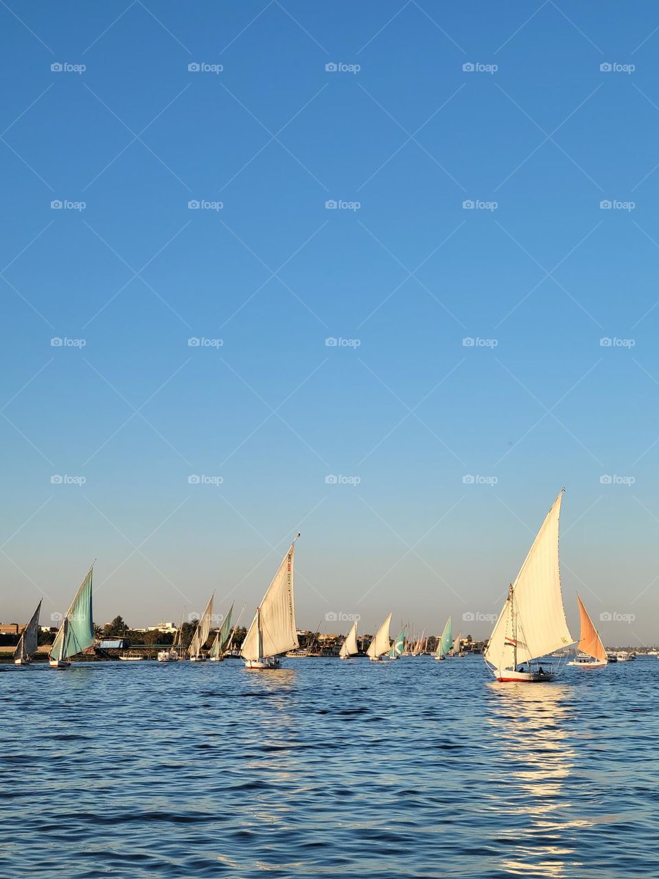 Cloudless sunny day - boat ride down Nile River seeing felucca at Luxor Egypt