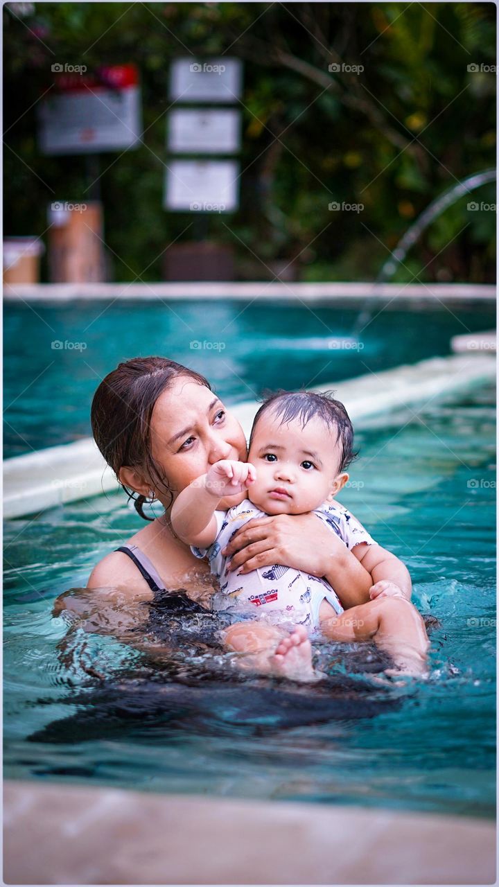 a happy mother and son enjoy playing in the swimming pool